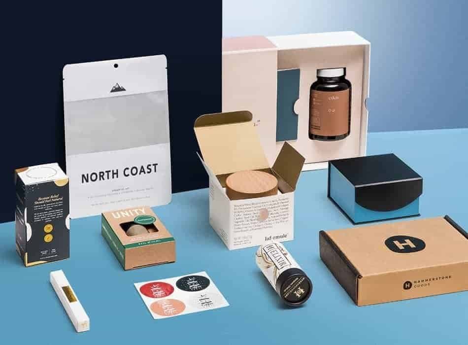 Custom printed boxes, pouches, mailers and stickers arranged on a blue surface